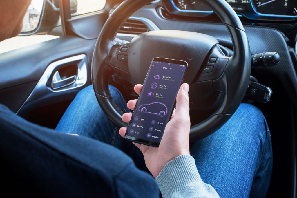 Ein Mann überprüft auf seinem Smartphone die Daten seines Autos.