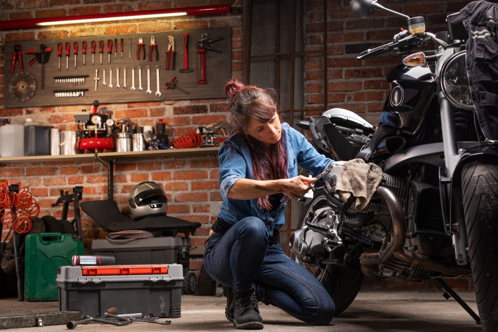 Eine Frau schraubt in einer Werkstatt an ihrem Motorrad.