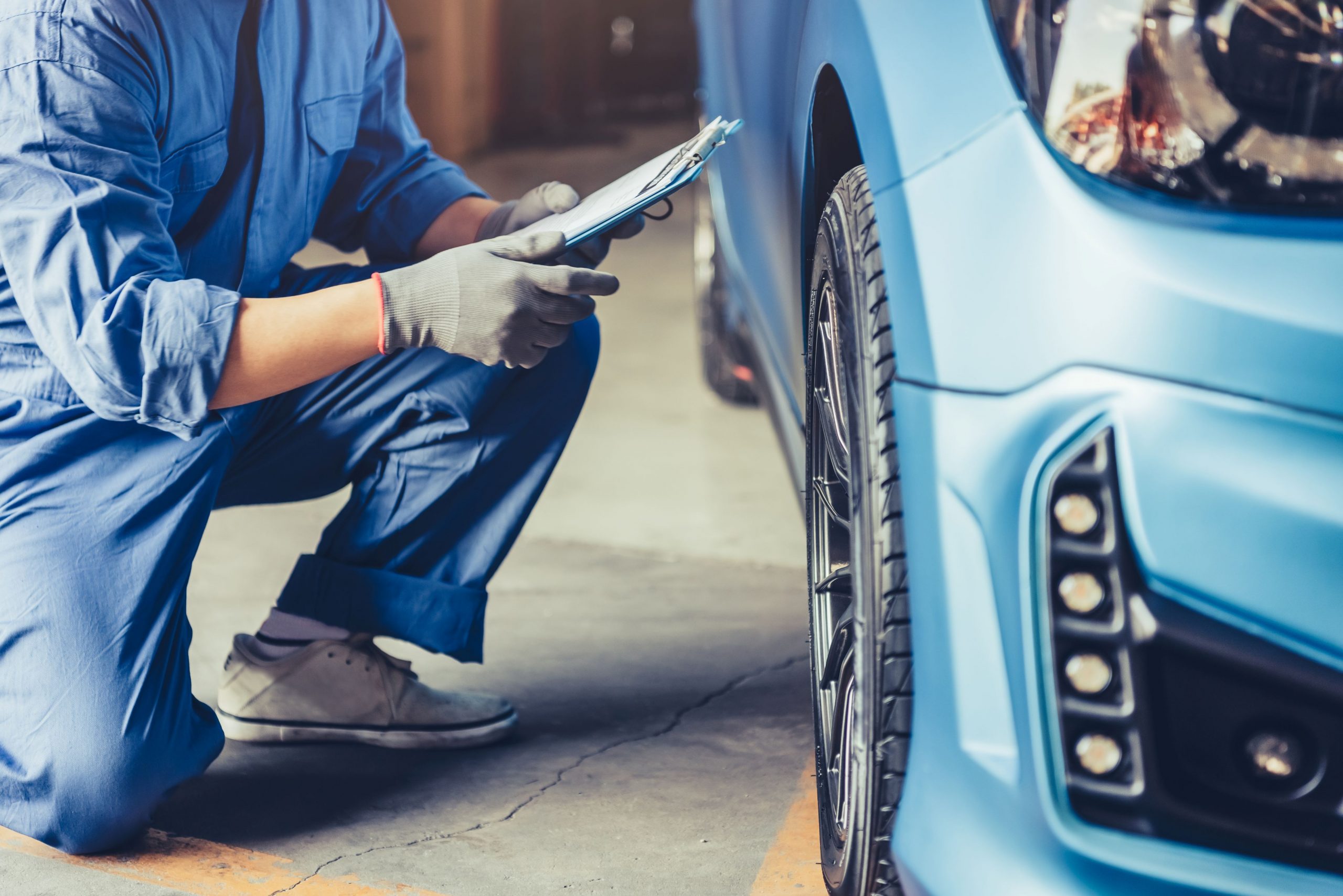 Ein Autohändler prüft den Zustand eines blauen Autos.